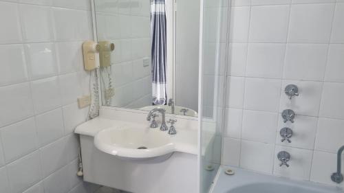 a white bathroom with a sink and a shower at Forstay Motel in Forster