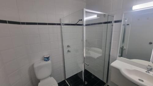 a bathroom with a shower and a toilet and a sink at Forstay Motel in Forster