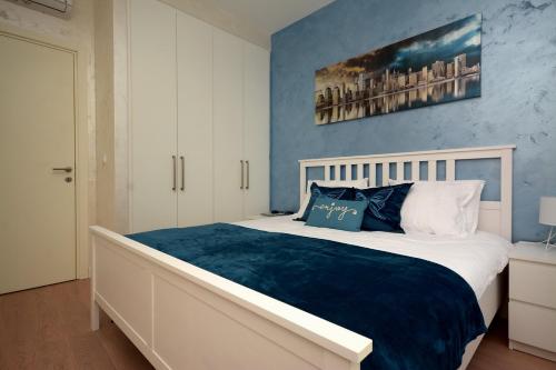 a bedroom with a large bed with a blue wall at GIGI Apartment in Belgrade
