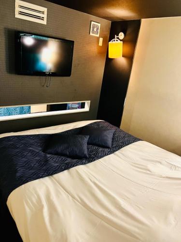 a hotel room with a bed and a flat screen tv at ホテル CROWN MOTEL in Yokohama