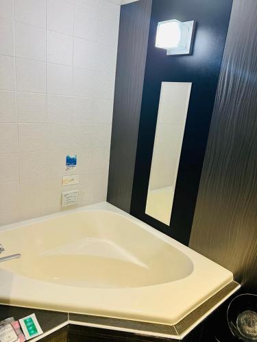 a large bath tub in a bathroom with a mirror at ホテル CROWN MOTEL in Yokohama