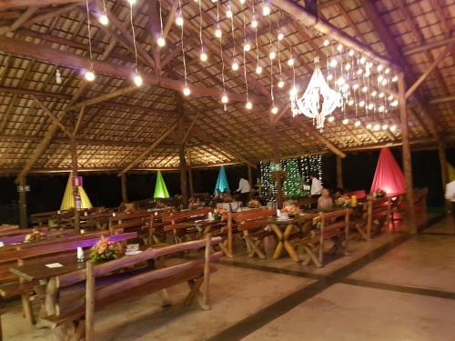 a restaurant with wooden tables and chairs and a chandelier at Hotel Fazenda Coninho in Inhaúma