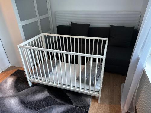 a white crib in a living room with a couch at luxurious 2-room apartment in central Borås in Borås