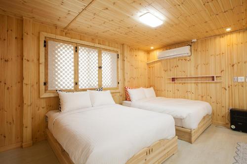 two beds in a room with wooden walls at Jeju Best Hill in Jeju