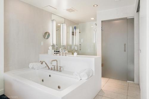 a white bathroom with a tub and a sink at Luxury Corner 1 BR W Residence with Fantastic Intercoastal Views, Pool & Hot tub in Fort Lauderdale