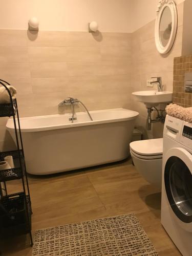 a bathroom with a tub and a sink and a washing machine at Luxury Old Town apartment in Vilnius