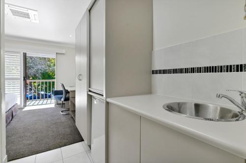 a white kitchen with a sink and a table at Central Caleula Motor Lodge in Orange
