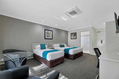 a hotel room with two beds and a table and chairs at Central Caleula Motor Lodge in Orange