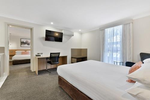 a hotel room with a bed and a desk and a mirror at Central Caleula Motor Lodge in Orange