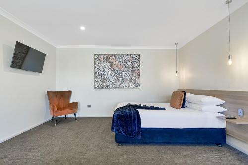 a hotel room with a bed and a chair at Central Caleula Motor Lodge in Orange