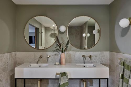 a bathroom with two sinks and two mirrors at Central Caleula Motor Lodge in Orange