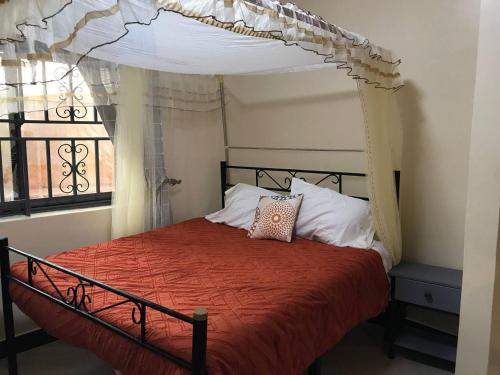 1 dormitorio con cama con dosel y ventana en Amazing lake Victoria Villa, Entebbe en Entebbe