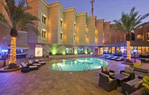 a hotel courtyard with a swimming pool and palm trees at Holiday Inn Al Khobar by IHG in Al Khobar