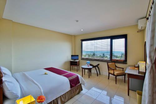 ラブハン・バジョにあるザ ジャヤカルタ スイーツ コモド フローレスのベッド、デスク、窓が備わるホテルルームです。