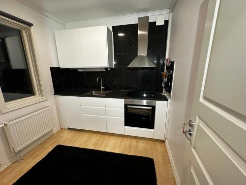 a kitchen with white cabinets and a sink at luxurious 2-room apartment in central Borås in Borås