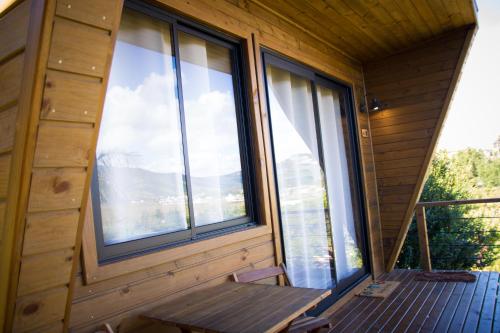 a bench on the porch of a cabin with large windows at Pousada Colina Verde in Garopaba