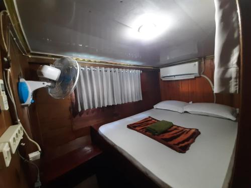 a small room with a bed and a fan at Boat Open Trip Komodo 3Days 2 Nigths in Labuan Bajo