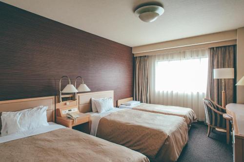 Habitación de hotel con 2 camas y ventana en Numazu River Side Hotel, en Numazu