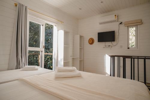 a bedroom with two beds and a tv on the wall at Pousada Colina Verde in Garopaba