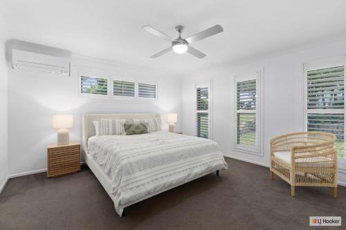 a white bedroom with a bed and a chair at Casa Palmera in Casuarina
