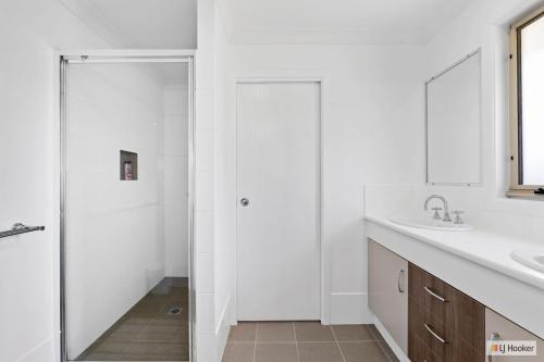 a white bathroom with a shower and a sink at Casa Palmera in Casuarina