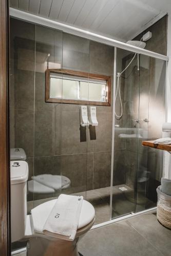 a bathroom with a toilet and a glass shower at Pousada Colina Verde in Garopaba
