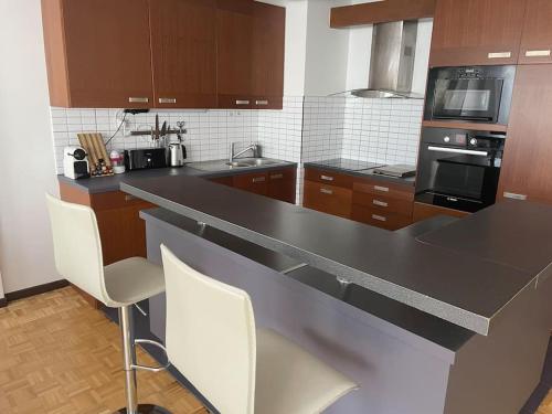 - une cuisine avec un comptoir noir et des chaises dans l'établissement HEADS PROPERTY - Full Appart 72 m2, à Levallois-Perret