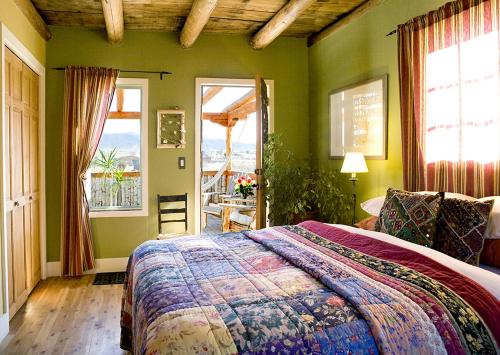 1 dormitorio con 1 cama grande, paredes y ventanas verdes en Casa Gallina - An Artisan Inn, en Taos