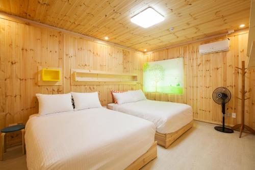 2 camas en una habitación con paredes de madera en Jeju Best Hill en Jeju