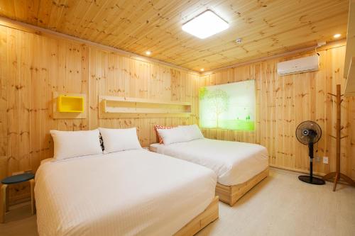 two beds in a room with wooden walls at Jeju Best Hill in Jeju