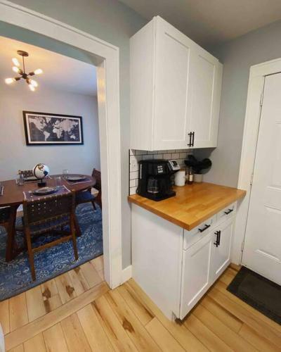 a kitchen with white cabinets and a dining room with a table at Holy City Bungalow in Charleston
