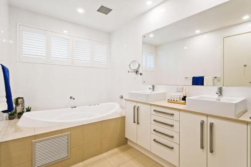 a bathroom with two sinks and a large mirror at Belle Escapes - Paradise on the Beach in Somerton Park