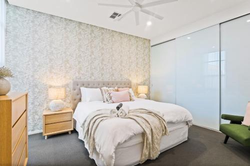 a bedroom with a white bed and a green chair at Belle Escapes - Paradise on the Beach in Somerton Park