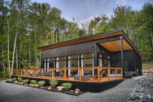 a house in the woods with a black at KALLM-Mont-Tremblant chalet with hot tub, pond & beach on private 7acre estate in Lac-Superieur