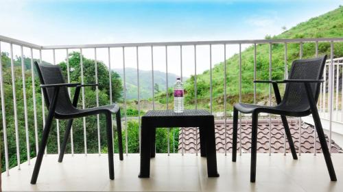 two chairs and a table with a bottle of water on a balcony at Glashaus by Izan in Vagamon
