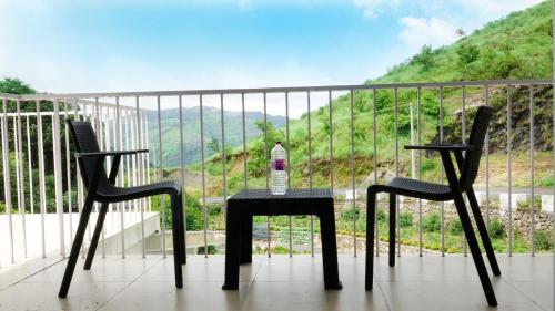 a table and two chairs on a balcony with a bottle of wine at Glashaus by Izan in Vagamon