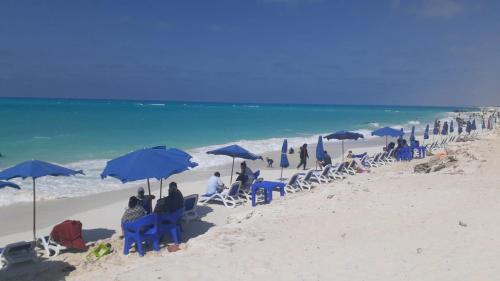 a group of people sitting in chairs and umbrellas on a beach at اكوا فيو الساحل الشمالي ك 91 العلمين in El Alamein