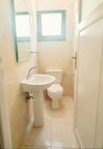 a white bathroom with a toilet and a sink at Chalet 3 bedrooms 2 toilets lotus north cost stand alone 3 Ac 2 stand fan families are preferred in El Alamein