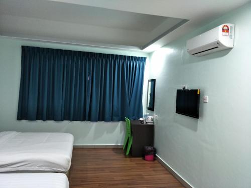 a room with a bed and a window with blue curtains at Salim Room in Sibu