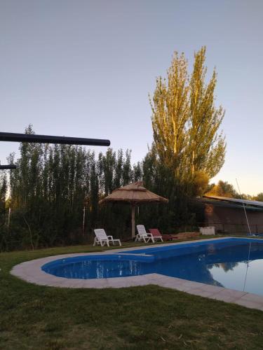 una piscina con 2 sillas y una sombrilla en San Rafael en San Rafael