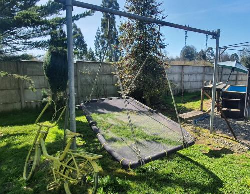 Un columpio en un patio con una bicicleta. en Agradable Cabaña campestre a 7 minutos de Osorno en Osorno