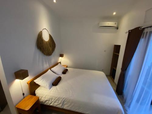 a bedroom with a white bed with a wooden headboard at Five Rooms in Canggu