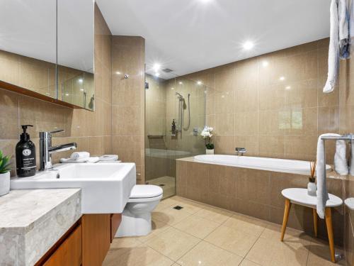 a bathroom with a sink and a toilet and a tub at Cotton Beach 94 Mid-Floor Penthouse with Bush View in Casuarina