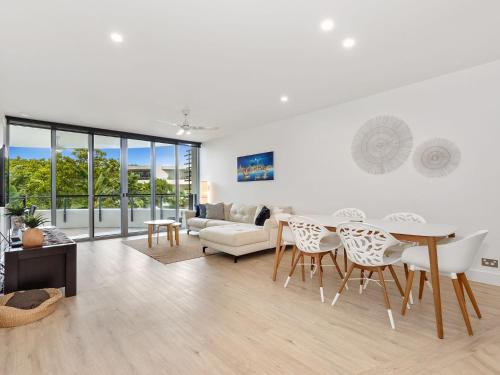 a white living room with a table and chairs at Cotton Beach Apartment 33 With Pool Views in Casuarina