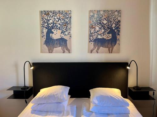 a bedroom with a bed with two paintings on the wall at Hotell Siesta in Karlskrona