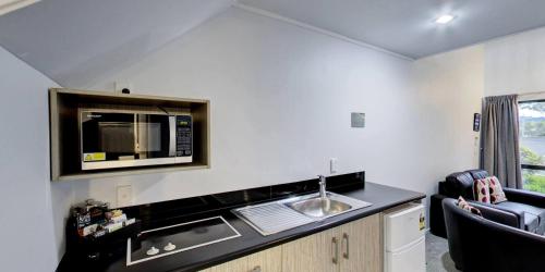 a small kitchen with a sink and a microwave at Arista of Rotorua in Rotorua