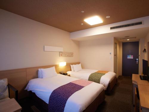 a hotel room with two beds and a tv at Kyoto Hot Spring Hatoya Zuihokaku Hotel in Kyoto