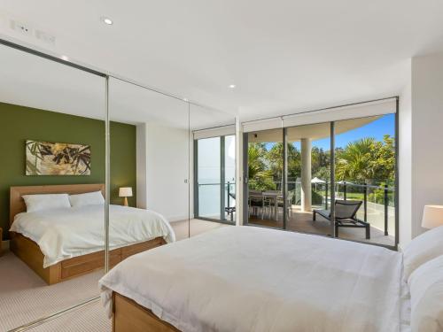 a bedroom with two beds and a balcony at Cotton Beach on the Pool 66 in Casuarina