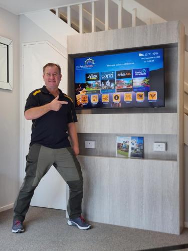 a man standing next to a wall with a tv at Arista of Rotorua in Rotorua