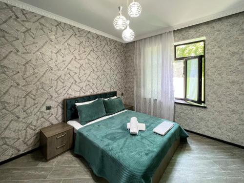a bedroom with a bed with a green comforter at Gabala villa in the center in Gabala